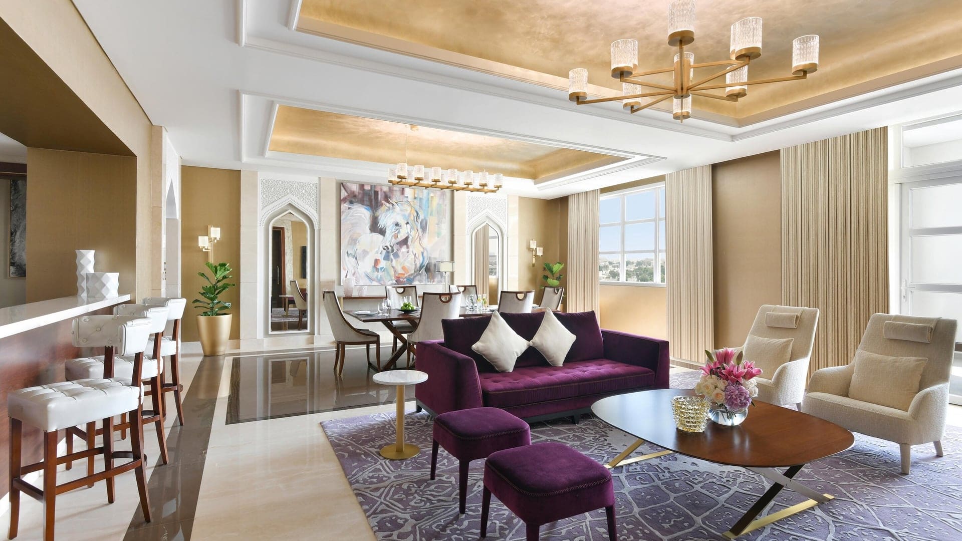 Living room, and dining area inside Al Messila Resort with artistic purple couches and large painting.