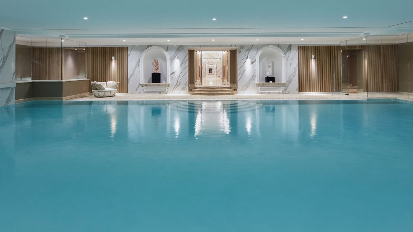 A infoor swimming pool with walls made of white marble.